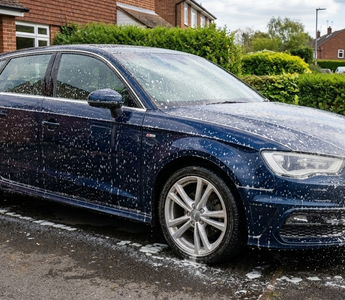 Detailer spraying citrus pre wash on a car and leaving it to dwell
