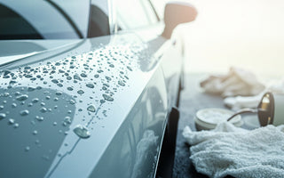shiny car surface with water beads and cleaning products in bright natural light